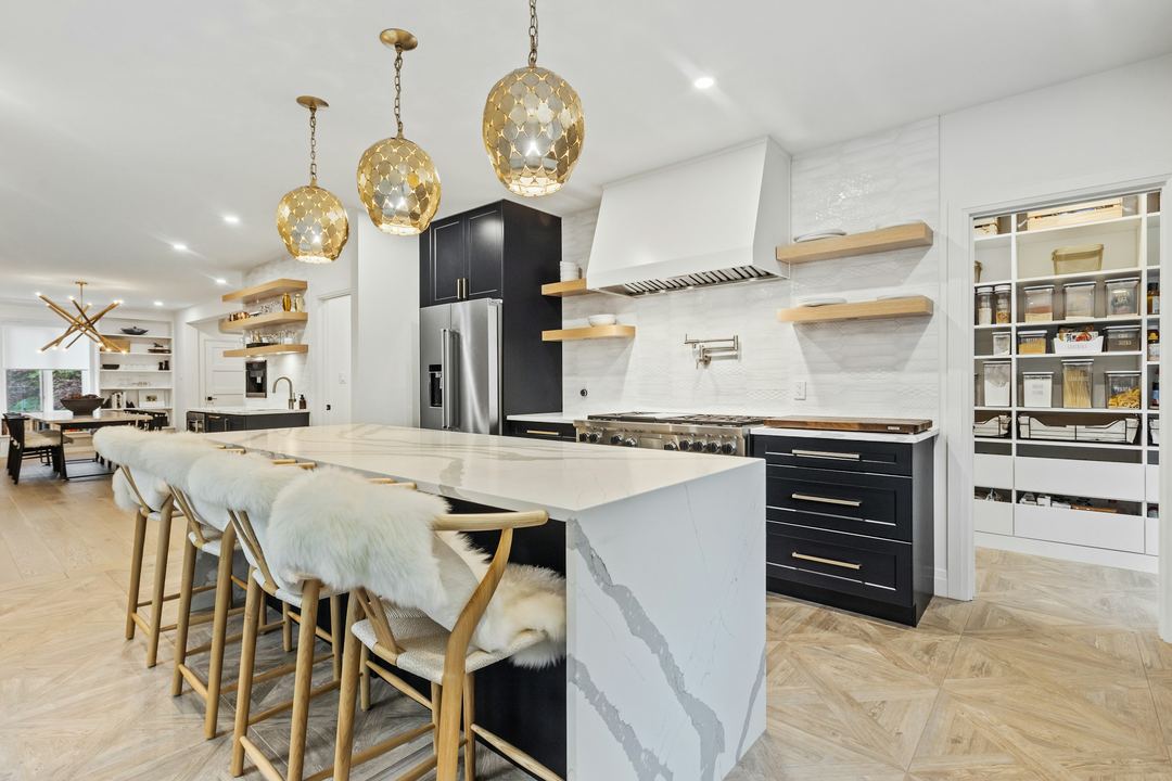 A white kitchen with brass pendant lights and a long island