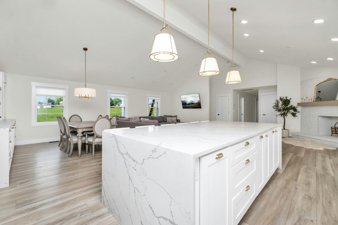 A white kitchen with a marble waterfall island
